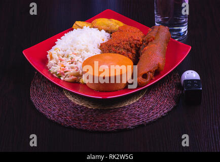 Popolari piatti nigeriani - un overhead shot di un piatto di riso bianco Dodo, Moi-Moi, insalata e carni assortite. Foto Stock