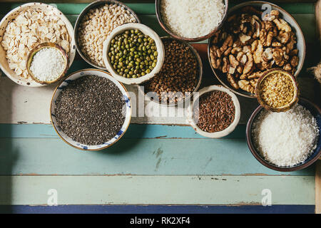 Varietà di materie non cotti i grani di cereale super chia semi di sesamo, Mung bean, noci, tapioca, frumento, grano saraceno, fiocchi d'avena, noce di cocco, riso in ceramica b Foto Stock