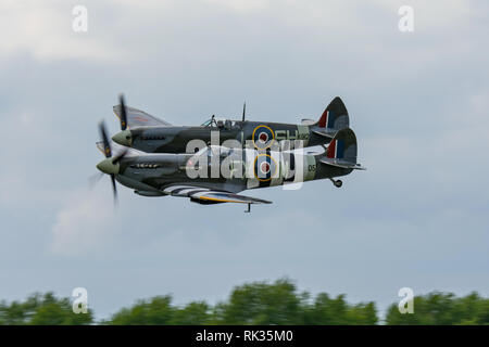 Due WW2 Supermarine Spitfire combattenti battenti in stretta formazione a basso livello sopra Biggin Hill Airfield,Kent, Regno Unito il 13 giugno 2015. Foto Stock