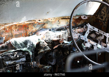 All'interno di bruciato relitto del furto di auto. Scena del Crimine immagine dell'interno del veicolo ha rovinato da un incendio o arson. La plastica fusa e metallo e volante Foto Stock