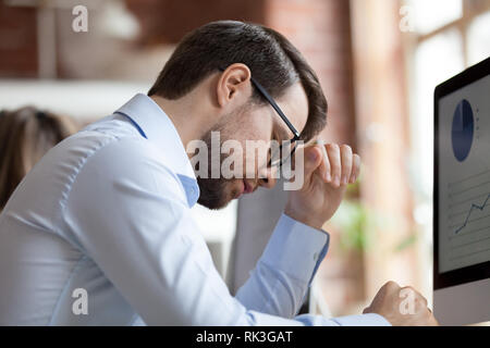 Sottolineato stanco imprenditore che soffrono di mal di testa emicrania al lavoro Foto Stock
