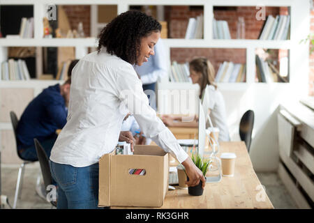 Felice giovane nero esordiente disimballaggio box con effetti personali al lavoro Foto Stock