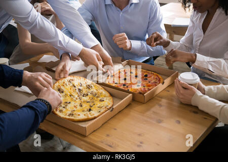 Diverse persone dello staff condividere pizza mani tenendo le fette dalla scatola Foto Stock