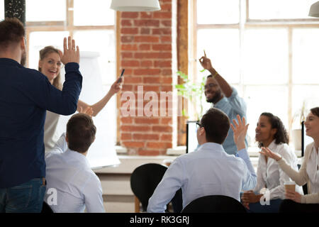 La gente di affari alzando le mani il voto di porre domande alla formazione aziendale Foto Stock