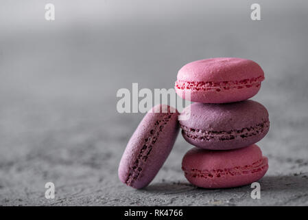 Bella colorata deliziosi dessert makarons, stack sulla pietra grigia sullo sfondo. Foto Stock