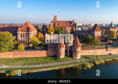 Medieval Malbork (Marienburg) castello in Polonia, fortezza principale dei Cavalieri Teutonici presso il fiume di Nogat. Vista aerea in caduta nella luce del tramonto. Foto Stock