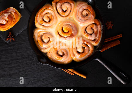 Concetto di alimenti freschi di forno in casa panini alla cannella in una padella in ghisa con pan di spazio di copia Foto Stock