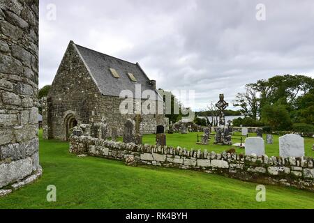 Le rovine di una chiesa più antica e un cimitero sulla Isola Santa del Lough Derg in Irlanda, nella contea di Clare. Sulla sinistra una parte di una torre rotonda. Foto Stock