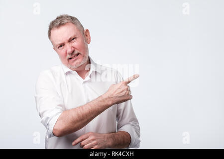 Uomo infelice si sente rammarico sulks face, espressione cupa, punti a parte Foto Stock