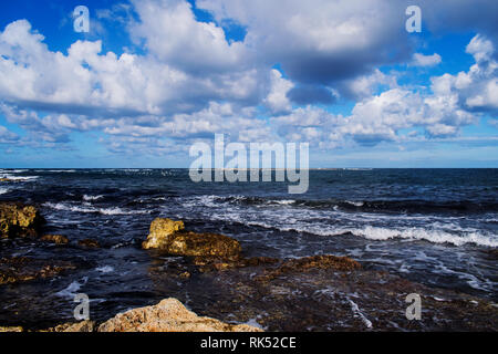 Un bellissimo paesaggio marino di Malta durante l'inverno con le onde in arrivo su ruvide rocce e cloudscape. Foto Stock