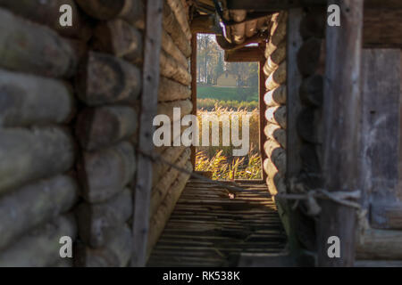 Vista la piccola casa in legno e la riva del lago attraverso la stretta corsia tra due vecchie baite di registro del lago antico Castello nel Araisi Museo Archeologico Foto Stock