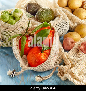 Frutta fresca e verdure organiche dal mercato locale confezionati in eco-friendly riutilizzabile sacchetti netto, visto da vicino su una superficie di legno Foto Stock