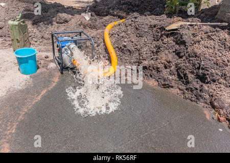 Plumbing lavori di movimento terra Scavo di trincee riparazioni delle rotte principali tubo acqua in strada residenziale area con motore mobile di pompaggio drenaggio sottovuoto danni. Foto Stock