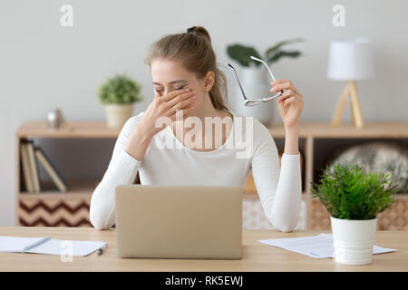 Stanco donna strofinarsi gli occhi di decollare bicchieri dopo il computer di lavoro Foto Stock