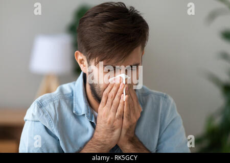 Uomo malato ha avuto influenza allergia starnuti nel fazzoletto soffia il naso Foto Stock