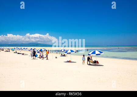 I turisti blu e bianchi ombrelloni sulla spiaggia Kondoi, Isola di Taketomi (Isola di Taketomi-jima), Isole Yaeyama Prefettura di Okinawa in Giappone. Foto Stock