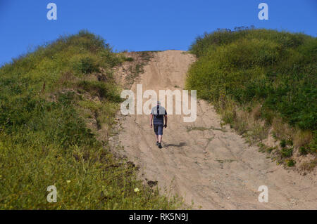 Maschio solitario escursionista a piedi su vasta via tra il WW2 Pleinmont tedesco le torri di osservazione sul sentiero costiero di Guernsey nelle isole del Canale. Regno Unito Foto Stock