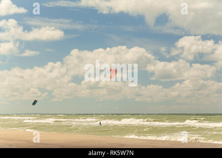 Le persone sono impegnate in kitesurf sul mare in tempesta Foto Stock