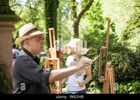 Un maschio maturo pittore che lavora su un cavalletto, al Central Park di New York Foto Stock