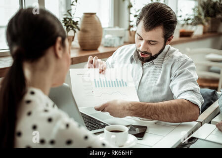 Attento businessman piegando la testa mentre raccontano il suo schema Foto Stock