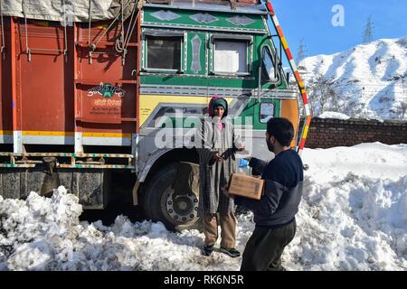 La questione del Kashmir, India. 9 Feb 2019. Un locale vede la distribuzione di cibo ad un filamento driver del carrello su una chiusa Autostrada nazionale in Qazigund, a circa 85km da Srinagar, Indiano Kashmir amministrato. La principale strada Nazionale che collega la valle con il resto del paese sono rimaste chiuse il sabato per il quarto giorno consecutivo dopo una valanga di uccidere sette persone inclusi i tre poliziotti, i due vigili del fuoco e dei due prigionieri. Credito: SOPA Immagini limitata/Alamy Live News Foto Stock