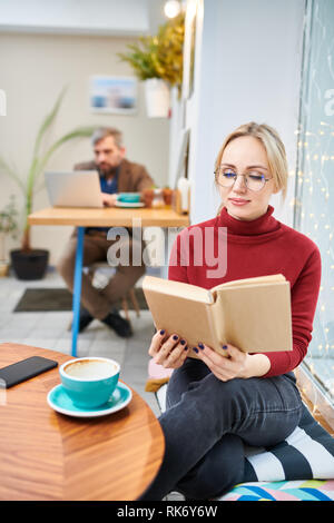 Donna lettura in cafe Foto Stock