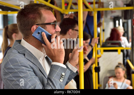 Imprenditore della tuta in piedi parlando al telefono cellulare sul tram trasporto rapido Foto Stock