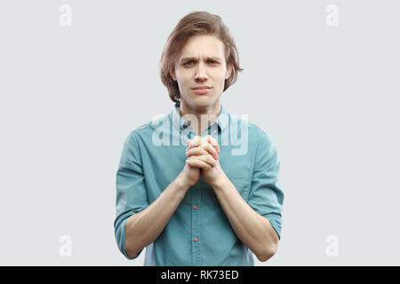 Please help me. Ritratto di speranzoso bello capelli lunghi biondo giovane in maglietta blu in piedi con la mano di Palm e di speranza per aiutare o perdono. indo Foto Stock