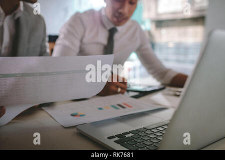 Due imprenditori lavorare insieme sui documenti presso la caffetteria. La gente di affari facendo alcune pratiche presso la caffetteria tabella con un computer portatile nella parte anteriore. Foto Stock