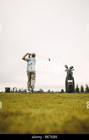 Uomo senior di mettere in pratica i suoi scatti a gamma di guida. Lunghezza completa di senior golfer maschio a fare pratica al campo da golf. Foto Stock