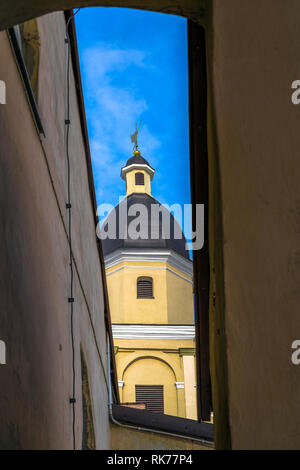 La torre di Santa Teresa la chiesa con un angelo attraverso l'arco nella città vecchia di Vilnius come visto dalla porta di Alba Foto Stock