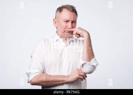 L'uomo pizzichi di naso con il dito guarda con disgusto puzza qualcosa di cattivo odore Foto Stock