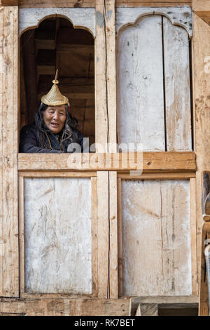 Vecchia donna Layap alla finestra della sua casa di Laya, Gasa distretto, Snowman Trek, Bhutan Foto Stock