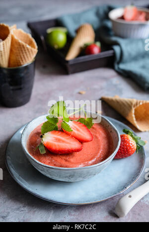 Dolce sorbetto di fragole decorate con la menta e waffle coni Foto Stock