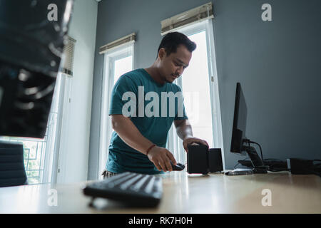 Ritratto di asian giovane uomo di risolvere un problema di personal computer in ufficio Foto Stock