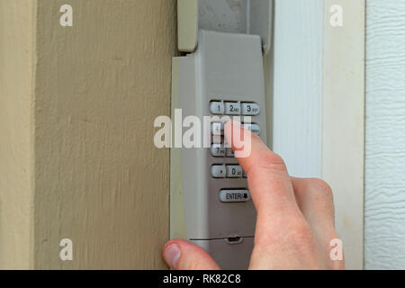 Mano immette il codice sul tastierino numerico utilizzato su una porta di garage ingresso di una casa - Tastiera di sicurezza - Codice di sicurezza Foto Stock