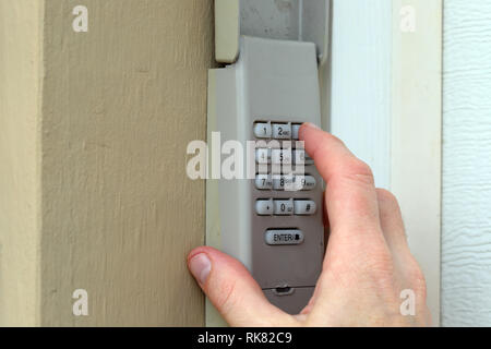 Mano immette il codice sul tastierino numerico utilizzato su una porta di garage ingresso di una casa - Tastiera di sicurezza - Codice di sicurezza Foto Stock