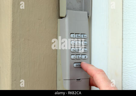 Mano immette il codice sul tastierino numerico utilizzato su una porta di garage ingresso di una casa - Tastiera di sicurezza - Codice di sicurezza Foto Stock