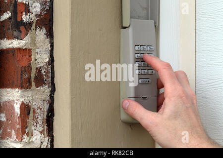 Mano immette il codice sul tastierino numerico utilizzato su una porta di garage ingresso di una casa - Tastiera di sicurezza - Codice di sicurezza Foto Stock