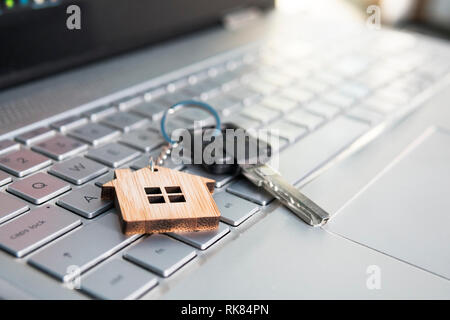 Concetto di ipoteca con chiavi e casa-chiave a forma di anello sulla tastiera del notebook. Trovare casa da sogno nel concetto di internet. Assistenza online nella ricerca di abitazione Foto Stock