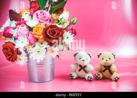 Vaso di bouquet di rose in alluminio benna e coppia adorabile Orso su sfondo rosa. Il giorno di San Valentino del concetto. Foto Stock