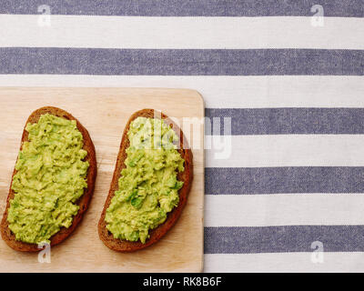 Sandwich con il guacamole su luce sfondo tessili vista superiore panini sulla tavola di legno Foto Stock