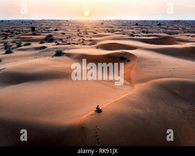 Donna guardando il tramonto nel deserto vista aerea Foto Stock