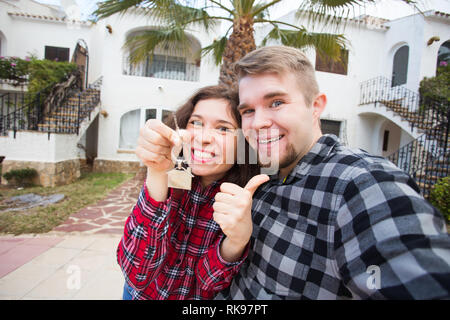 Immobiliare di proprietà e di concetto - coppia felice tenendo premuto i tasti per nuova casa e casa miniatura Foto Stock