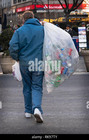 Un anonimo uomo di mezza età raccolta deposito vuoto bottiglie e lattine nei pressi di Herald Square a Manhattan, New York City. Foto Stock