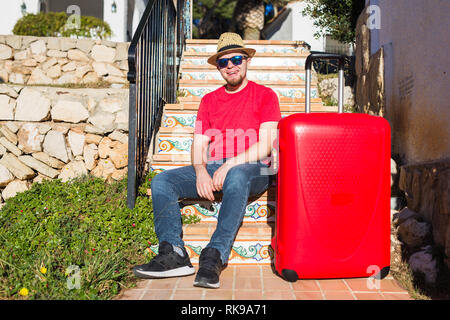 Vacanze, Viaggi, concetto di persone - il giovane uomo seduto sulle scale con le valigie Foto Stock