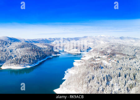Inverno bellissimo paesaggio panoramico in montagna, lago Lokvarsko in Croazia, boschi sotto la neve nella regione di Gorski kotar e Risnjak mountain in background Foto Stock