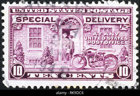 Portalettere consegna la posta in moto su di noi vintage francobollo Foto Stock