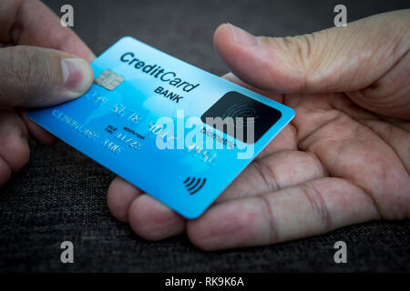 La carta di credito è incorporato uno scanner di impronte digitali. Illustrazione del pagamento biometrici sicurezza. Una mano maschio è titolare di carta blu e altri tocchi scanne Foto Stock