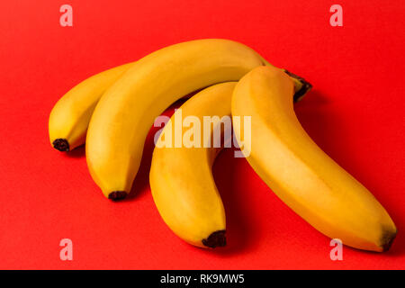 Il minimalismo creativi concetto. Concetto di imprevisti. Appartamento vista laici di banana frutto pattern su sfondo rosso. Foto Stock